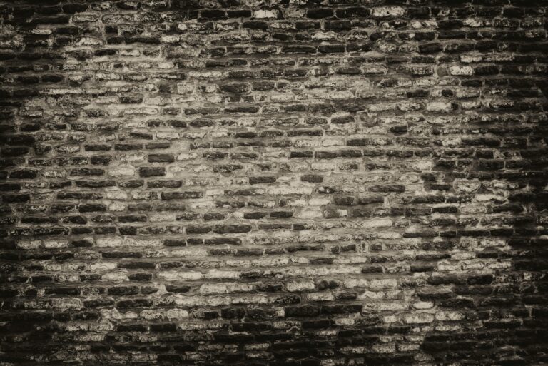 Grayscale textured brick wall background with rough surface.