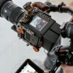 Close-up of a modern video camera setup capturing a group in an indoor setting.